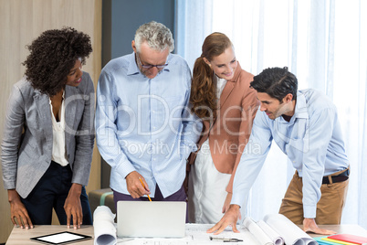 Businesswoman and coworker discussing blueprint on the desk Businesswoman and coworker discussing blueprint on the desk