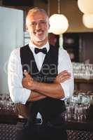 Portrait of bartender standing with arms crossed