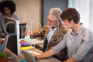 Businessman explaining colleagues over computer