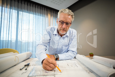 Architect working on blueprint at desk