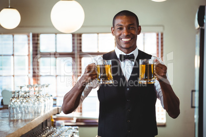 Smiling bartender offering a two glass of beer at bar counter