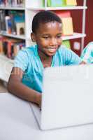 Schoolboy using laptop in library