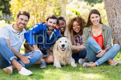 Group of happy friends sitting together with the dog