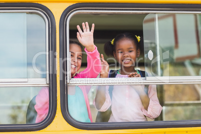 Portrait of school kids waving hand from bus