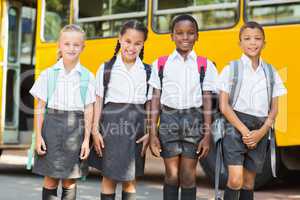 Smiling kids standing together in front of school bus