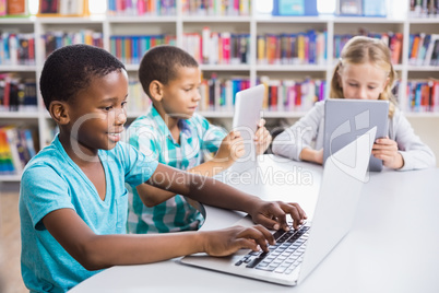 Kids using laptop and digital tablet in library