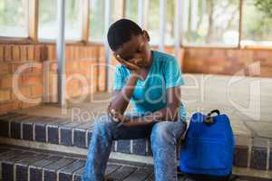 Sad schoolboy sitting alone on staircase