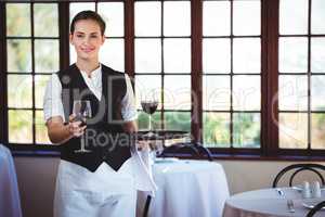 Portrait of smiling waitress offering a glass of red wine