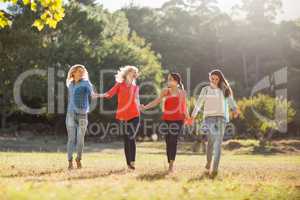 Beautiful women holding hands and walking together in park