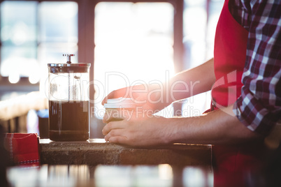 Mid section of waiter preparing coffee