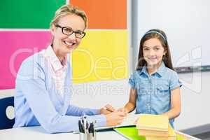 Teacher assisting schoolgirl in drawing