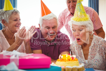 Senior woman blow on birthday cake