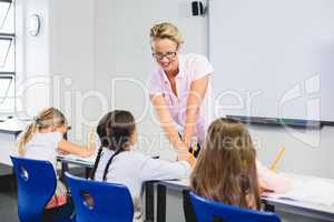 Teacher helping kids with their homework in classroom