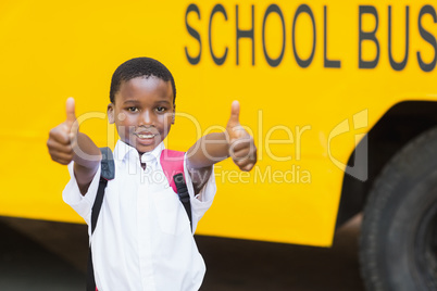 Smiling schoolboy showing thumbs up in front of school bus Smiling schoolboy showing thumbs up in front of school bus
