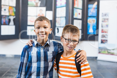 Smiling school kids standing with arm around in classroom