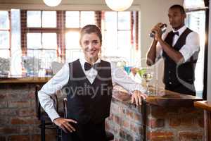 Smiling female bartender standing at bar counter