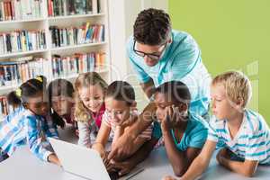 Teacher and kids using laptop in library
