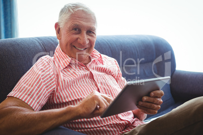 Senior man seated on a sofa looking at camera