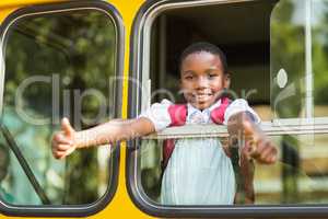 Smiling schoolboy showing thumbs up from bus