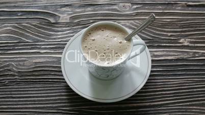 A cup of cappuccino with foam is on the table