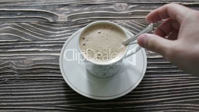 A cup of cappuccino with foam is on the table