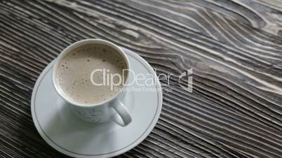 A cup of cappuccino with foam standing on vintage table