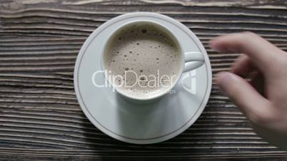 A cup of cappuccino with foam is on the table