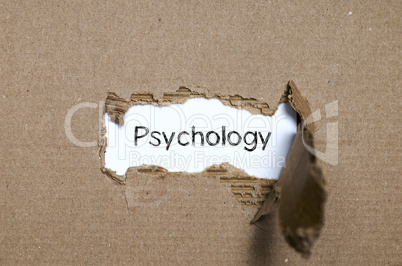 The word psychology appearing behind torn paper.