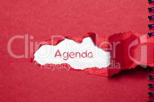 The word agenda appearing behind torn paper