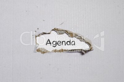 The word agenda appearing behind torn paper