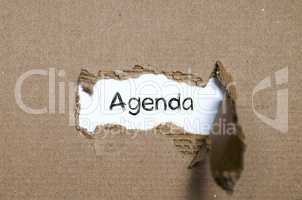 The word agenda appearing behind torn paper