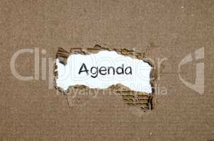 The word agenda appearing behind torn paper