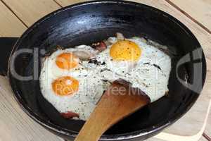 Fried eggs with bacon on the pan -  hearty breakfast