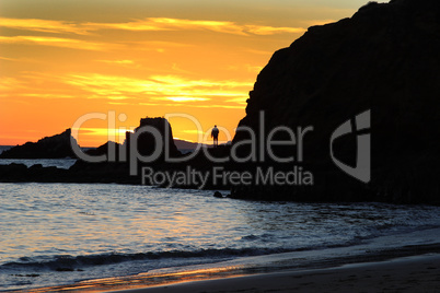 Silhouette of a man at sunset on a rock jetty at Shaw’s Cove