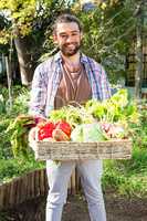 Portrait of confident gardener with vegetables in basket at gard