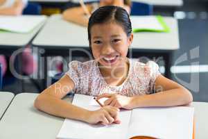 Smiling girl writing on book