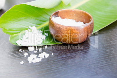 Bath salt in bowl with leaf on table