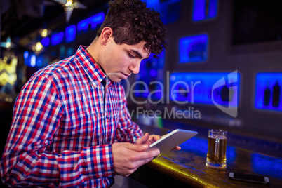 Young man using digital tablet at bar counter