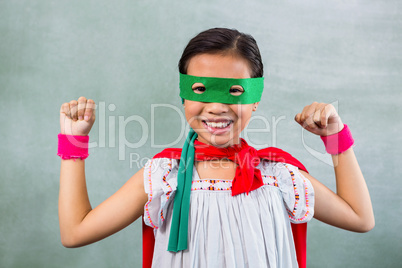 Happy girl dressed as superhero in classroom