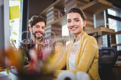 Happy creative business people sitting by desk