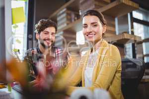 Happy creative business people sitting by desk