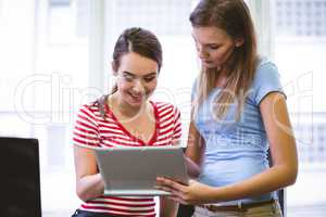 Happy executive showing colleague in tablet at creative office