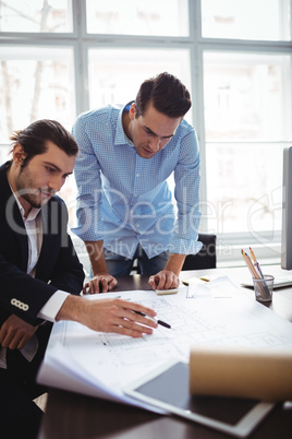 Interior designer explaining blueprint to male coworker