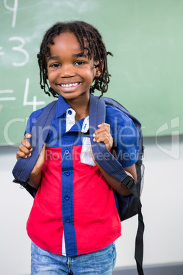 Smiling boy standing against board in classroom