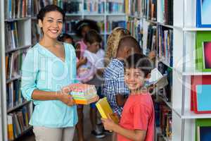 Smiling female teacher giving books to boy