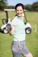Side view of cheerful woman carrying golf club