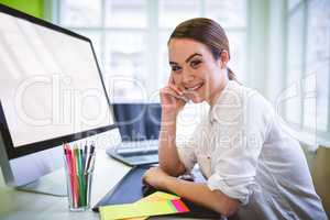 Female graphic designer talking on phone at desk