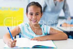 Portrait of smiling girl writing on book
