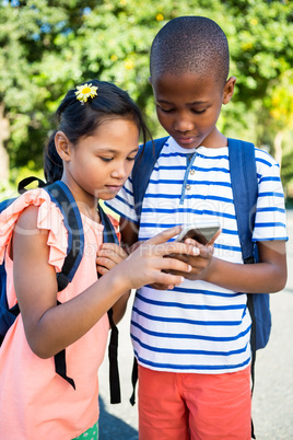 Schoolboy and girl using mobile phone at campus