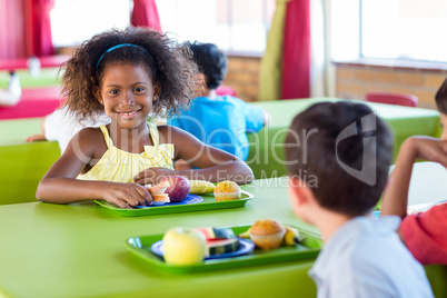 Smiling girl with classmates having meal